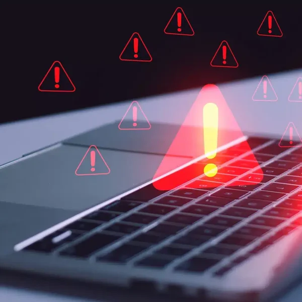 Clavier d'ordinateur portable avec plusieurs symboles d'avertissement rouges indiquant des alertes ou des problèmes, suggérant des malwares potentiels.
