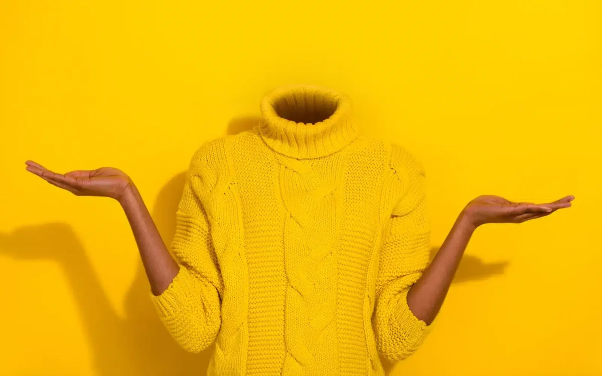 Une personne portant un pull jaune, avec une tête invisible, pose avec les bras tendus sur un fond jaune uni, reflétant les nouveautés vibrantes proches des dernières améliorations de WordPress 6.7.