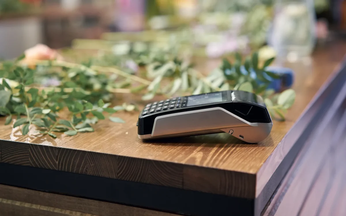Terminal de paiement par carte posé sur le comptoir en bois d’une boutique de fleurs, pour illustrer l’erreur lors du traitement d’une commande WooCommerce