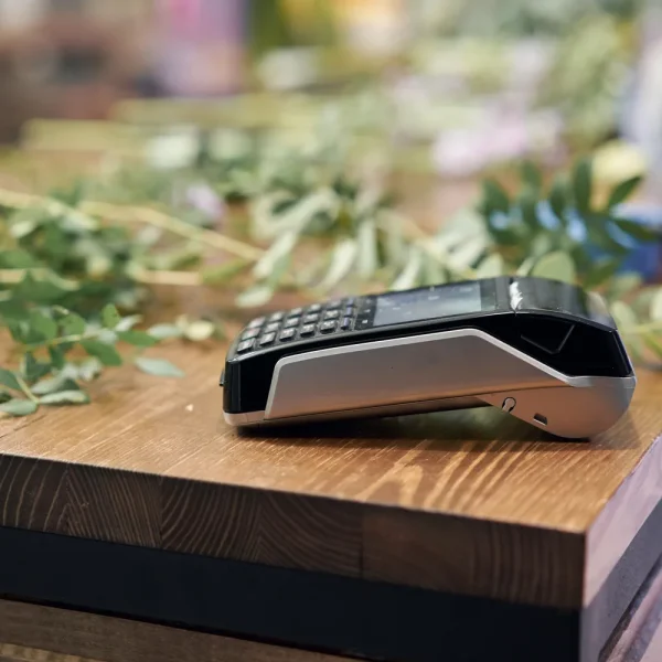 Terminal de paiement par carte posé sur le comptoir en bois d’une boutique de fleurs, pour illustrer l’erreur lors du traitement d’une commande WooCommerce