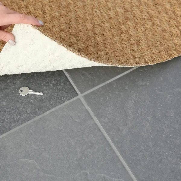 Main qui soulève un paillasson en fibre de coco et découvre une clé cachée sur le carrelage, pour illustrer les administrateurs cachés créés via la faille Ninja Forms
