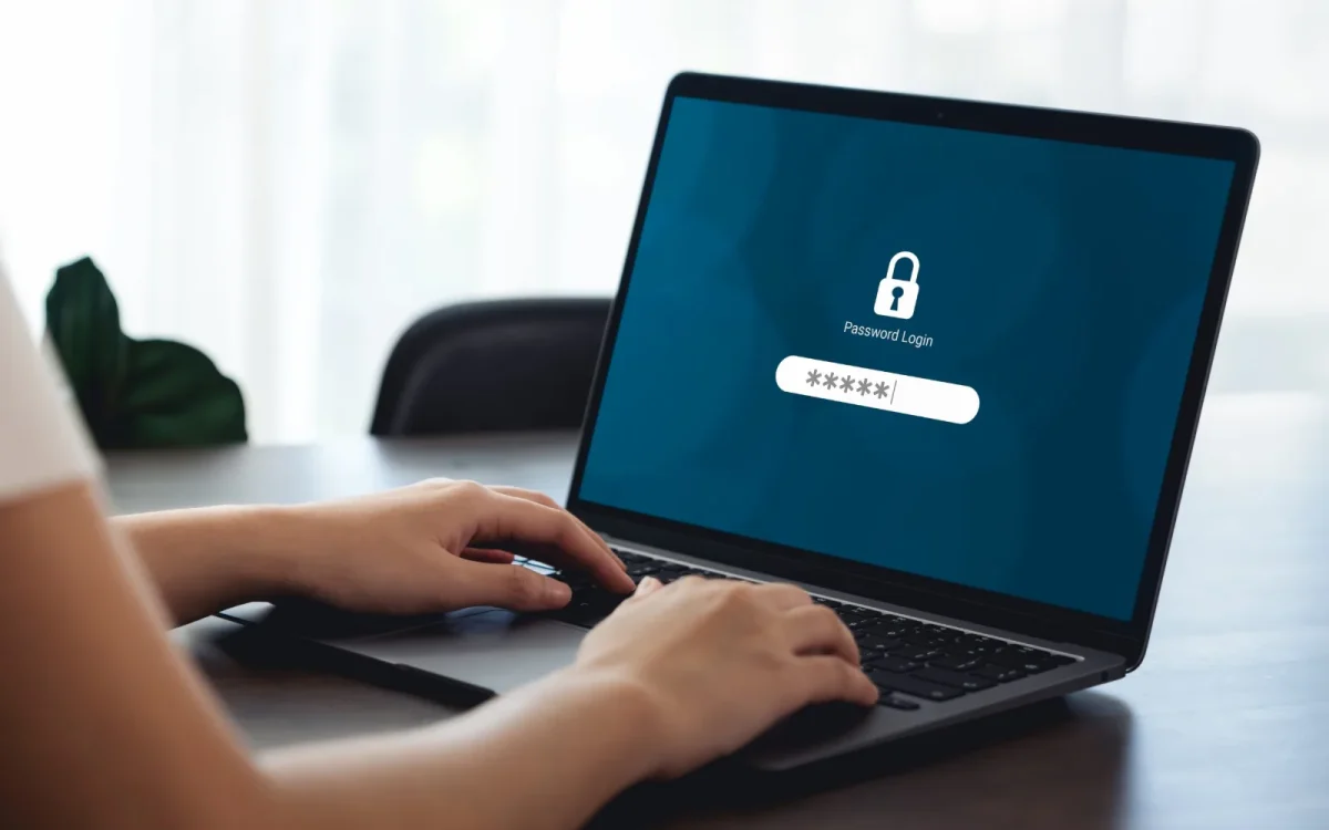 Mains sur le clavier d'un ordinateur portable affichant un écran de connexion verrouillé