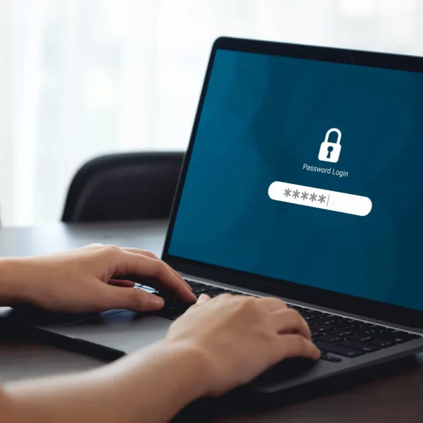 Mains sur le clavier d'un ordinateur portable affichant un écran de connexion verrouillé