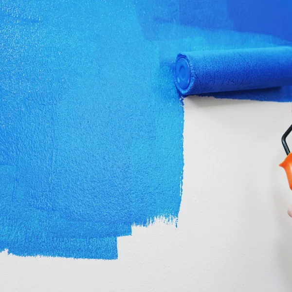 Rouleau de peinture qui recouvre un mur blanc de bleu vif, pour illustrer des modifications Elementor qui ne s'affichent pas sur le site
