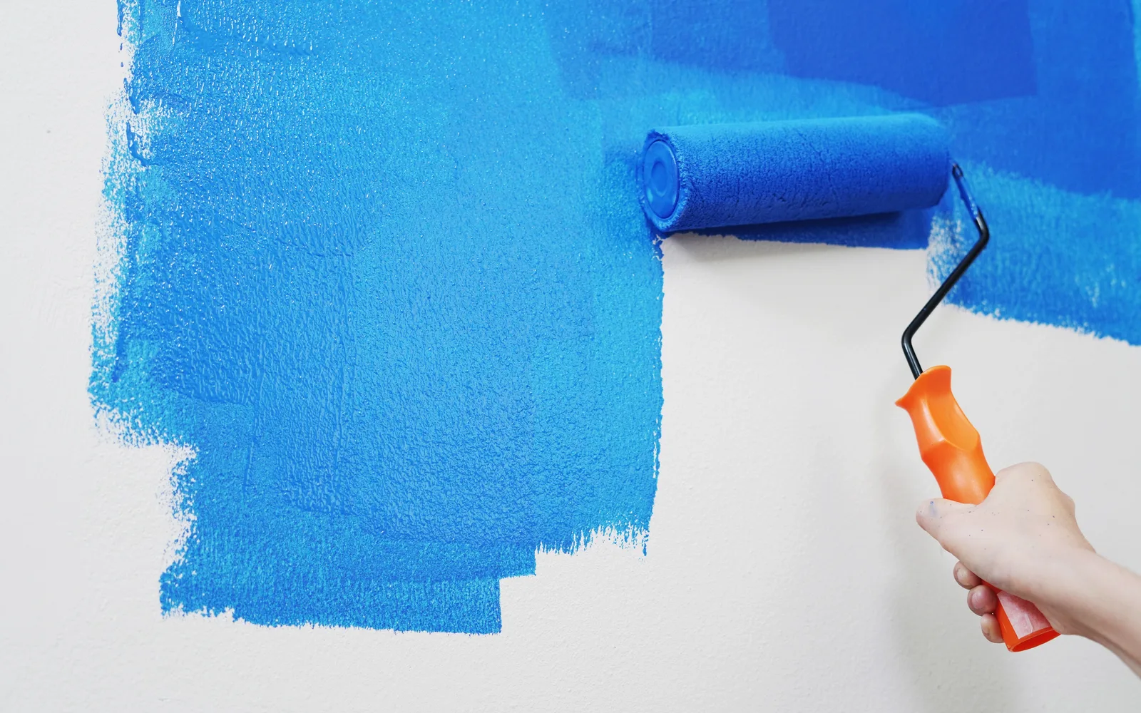Rouleau de peinture qui recouvre un mur blanc de bleu vif, pour illustrer des modifications Elementor qui ne s'affichent pas sur le site