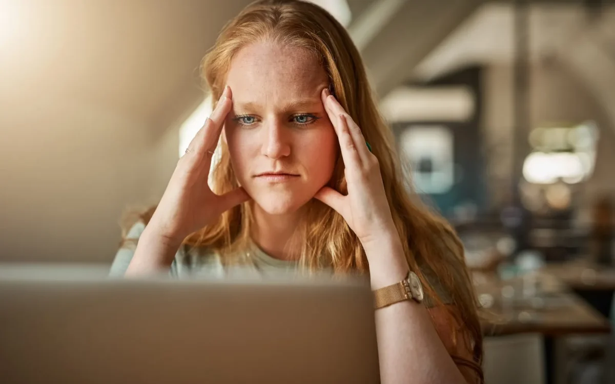 Femme stressée, la tête entre les mains devant son ordinateur portable, face à un problème de thème WordPress