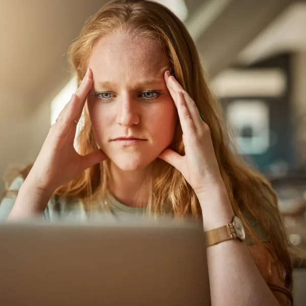 Femme stressée, la tête entre les mains devant son ordinateur portable, face à un problème de thème WordPress