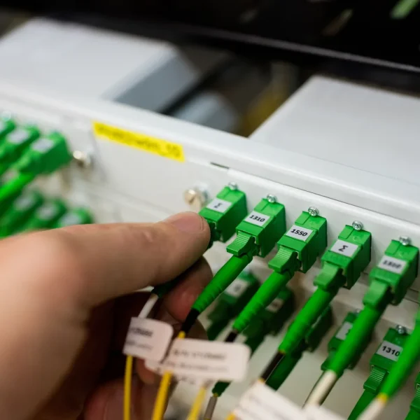 Main d'un technicien qui branche des câbles à fibre optique verts sur un panneau de brassage, image de la connexion coupée entre l'éditeur WordPress et le serveur