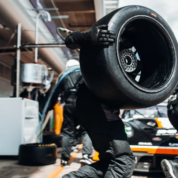 Mécanicien d'écurie qui court avec une roue lors d'un arrêt au stand de course automobile, pour illustrer l'accélération d'une boutique WooCommerce lente
