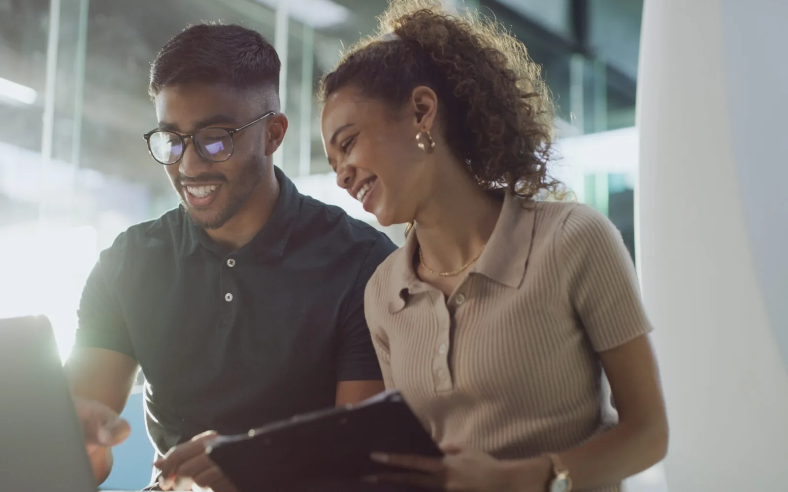 Deux membres d'une équipe souriants qui consultent une tablette, pour illustrer le suivi mensuel d'un site WordPress